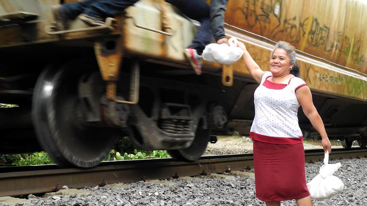 Jetzt muss es schnell gehen, denn der Güterzug bremst nur leicht ab: Die guten Samaritas von "Las Patronas" versorgen die notleidenden blinden Passagiere mit Lebensmittelpaketen und Wasserflaschen.