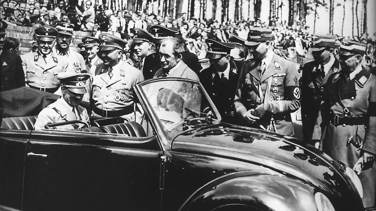 Ferdinand Porsche (in der Mitte ohne Kopfbedeckung) präsentiert 1936 dem Führer den ersten Käfer.