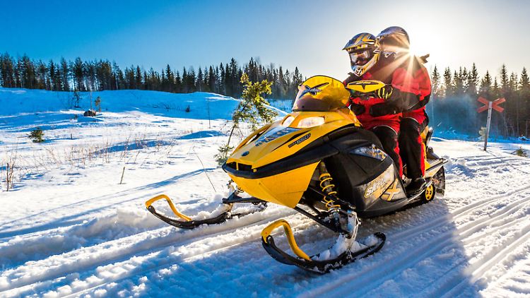 Warm eingepackt geht es mit dem Motorschlitten durch die eisige Winterlandschaft Kareliens an der Grenze zu Finnland.