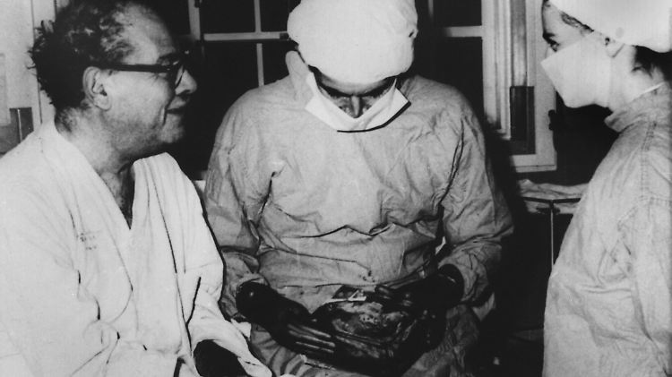Der südafrikanische Chirurg Christiaan Barnard (M) mit seinem zweiten Herztransplantations-Patienten Philip Blaiberg (l). Rechts eine Krankenschwester. In seinen Händen hält Barnard einen Beutel mit dem kranken Herzen, das er Blaiberg entnommen hatte.