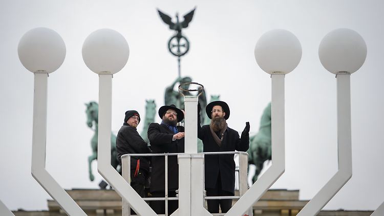 Yehuda Teichtal (M.) und ein weiterer Rabbiner weihen den Chanukka-Leuchter am Brandenburger Tor ein.