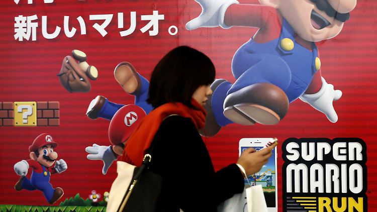 Eine Frau läuft an einem Werbeplakat für Super Mario Run in Tokio vorbei.