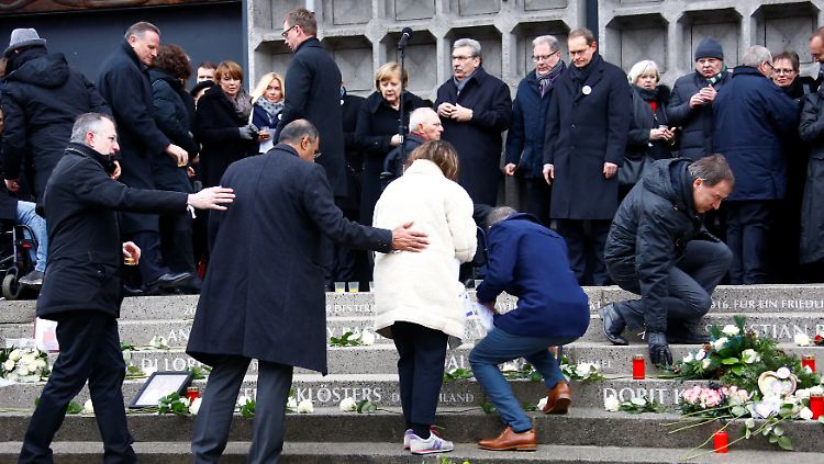 Menschen legen Blumen nieder auf den Stufen vor der Gedächtniskirche.