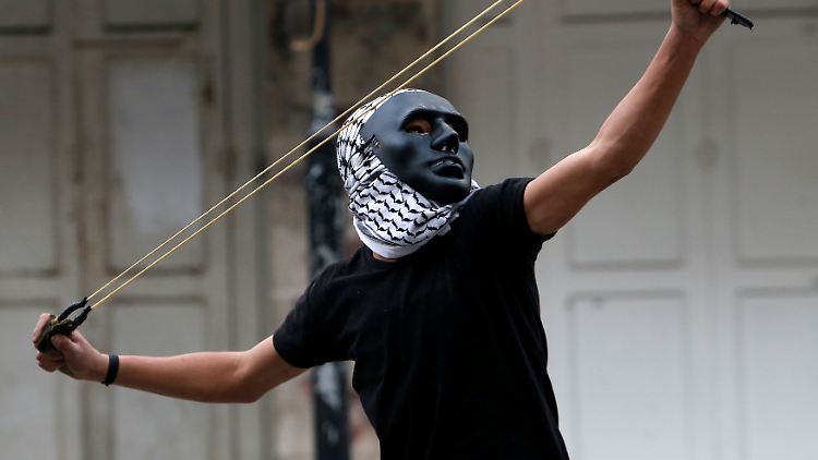 Ein Palästinenser schleudert Steine auf israelische Soldaten in Hebron.
