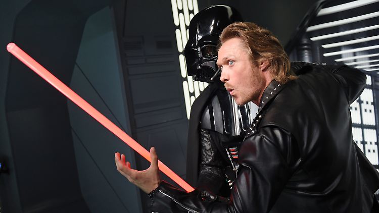 Nico Schwanz hält im Madame Tussauds Berlin an der Figur Darth Vader ein Lichtschwert in der Hand.