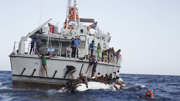 Libsche Flüchtlinge versuchen an Bord eines Schiffs der libyschen Küstenwache zu gelangen.