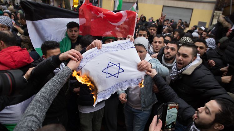 Teilnehmer einer antiisraelischen Demonstration in Berlin verbrennen eine Israel-Flagge. 