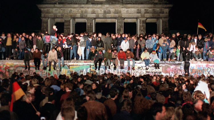Jubelnde Menschen stehen am 10. November auf der Mauer am Brandenburger Tor - am Tag zuvor war die Grenzbefestigung gefallen.