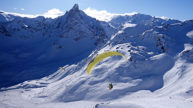 Neben Skifahren bietet der Ort auch viele andere Aktivitäten - Gäste können wie hier im Tandem-Paragleiter schweben oder Motorschlitten fahren.