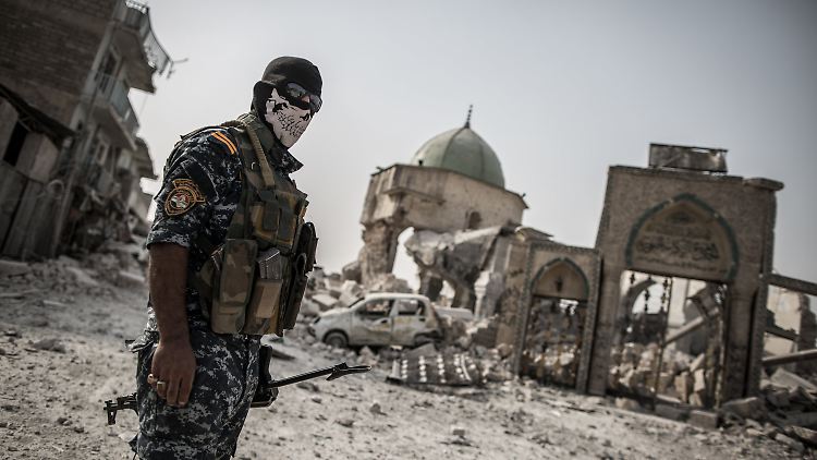 Mit einem Atemschutz steht ein irakischer Polizist vor den Trümmern der Al-Nuri-Moschee in Mossul.