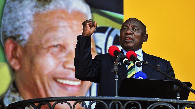 Ramaphosa spricht vor dem Hintergrund eines Mandela-Porträts.