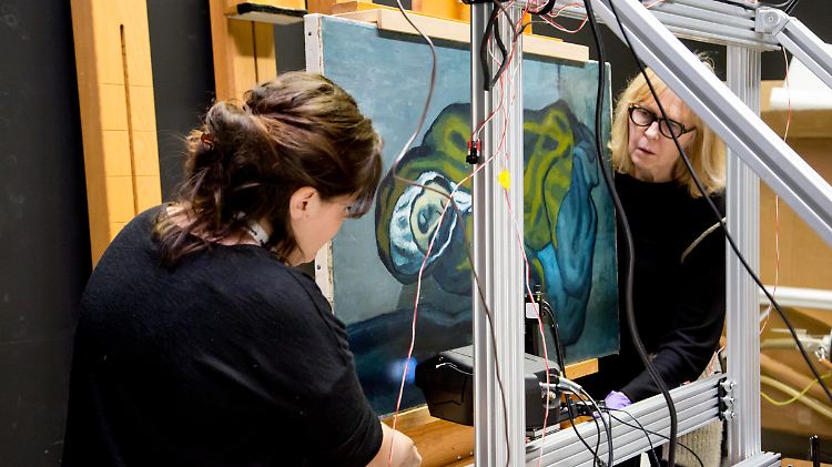 Emeline Pouyet (l) und Sandra Webster-Cook untersuchen das Picasso-Gemälde "La Miséreuse accroupie" (Die kauernde Bettlerin)" mit einem Rötgenfluoreszenzgerät.