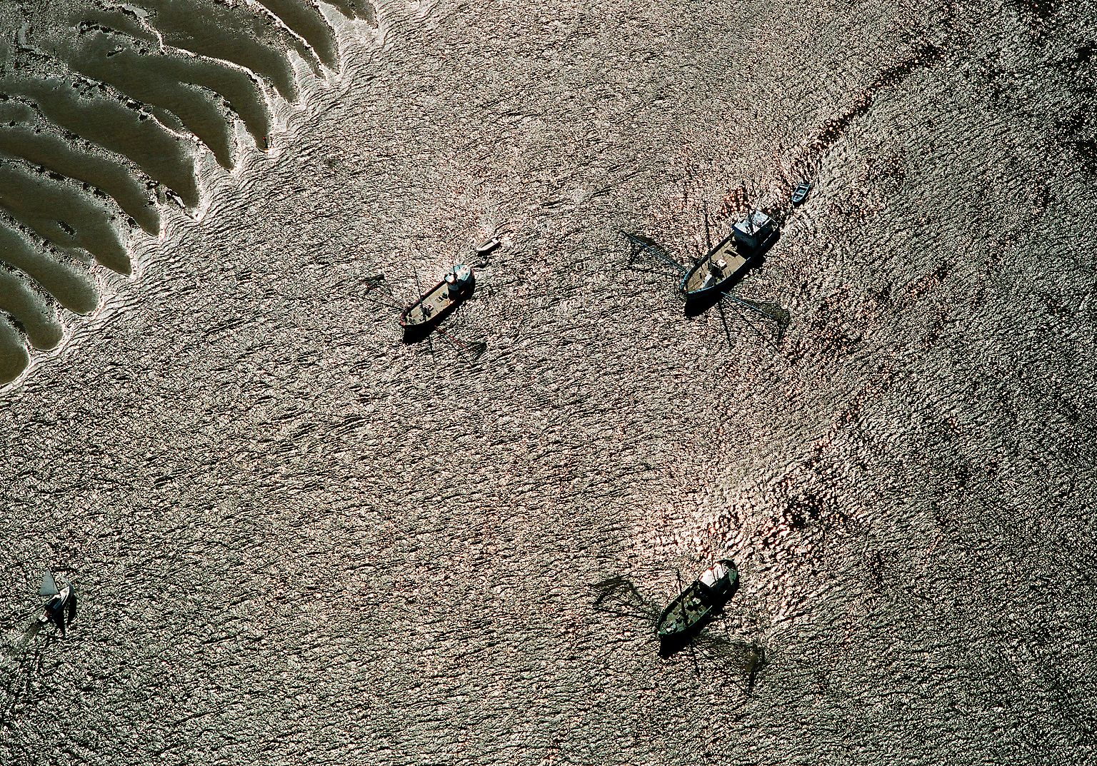 Im Bildband "Faszination Schleswig-Holstein - Eine Luftbildreise" wirft der Fotograf Reimer Wulf einen besonderen Blick auf das Bundesland: Silbrig schimmert die Wasseroberfläche der Elbe rund um diese Fischkutter. Nachdem die Elbfischerei wegen jahrzehntelang steigender Schadstoffbelastung nahezu am Ende war, steht es jetzt um die Qualität der Fische wieder besser. 