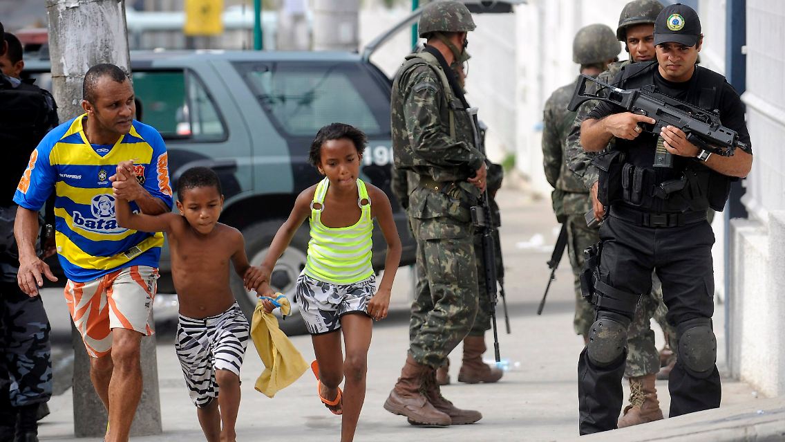 Ein Brasilianer bringt während einer Polizei-Aktion seine Kinder in Sicherheit.