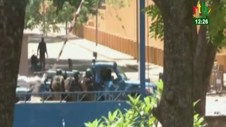 Fernsehbilder zeigen Sicherheitskräfte in Ouagadougou, die sich hinter einem Fahrzeug verschanzen.