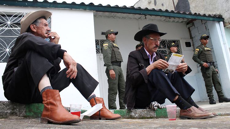 Interessierter Blick auf ein Flugblatt: Männer bei einer Wahlkampfveranstaltung der Farc.