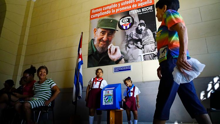 Ein Frau betritt in Havanna ein Wahllokal, um ihre Stimme abzugeben. Auf dem Plakat wacht der verstorbene Fidel Castro über sein Land.