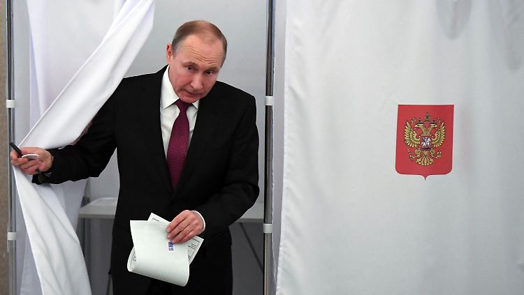 Präsident Wladimir Putin kommt aus der Wahlkabine, um seine Stimme abzugeben.