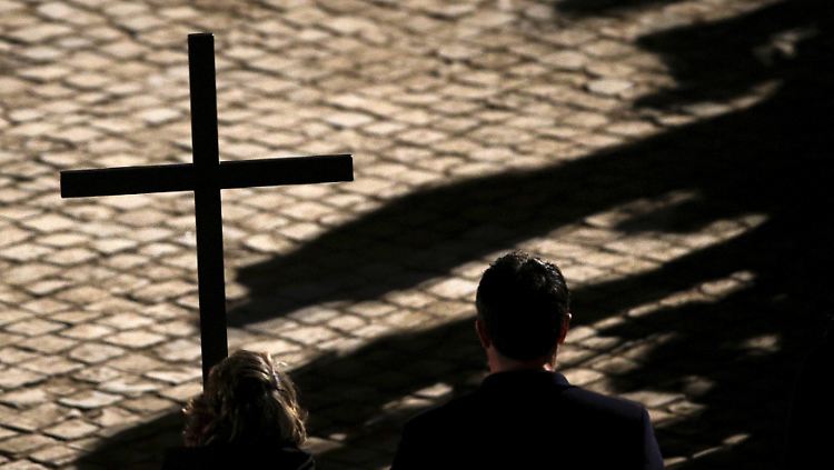 Gläubige tragen ein Kreuz bei einer Prozession.