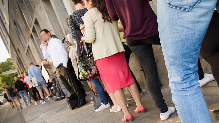 Menschen stehen sich vor einem Bürgeramt in München die Beine in den Bauch.