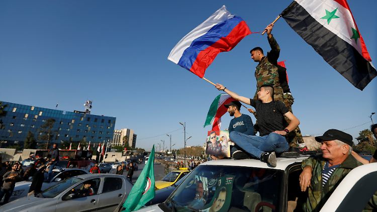 Anhänger des syrischen Regimes protestieren mit der syrischen und der russischen Flagge in der Hand gegen den Militärschlag der Westmächte.