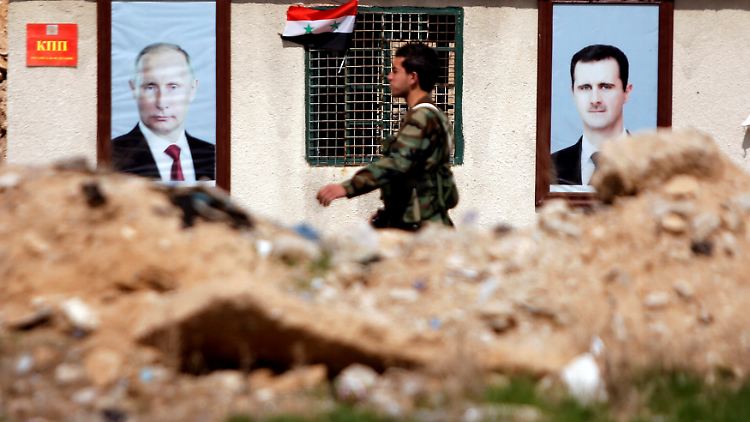 Ein syrischer Soldat in Damaskus vor Plakaten mit Russlands Präsident Putin und Assad.