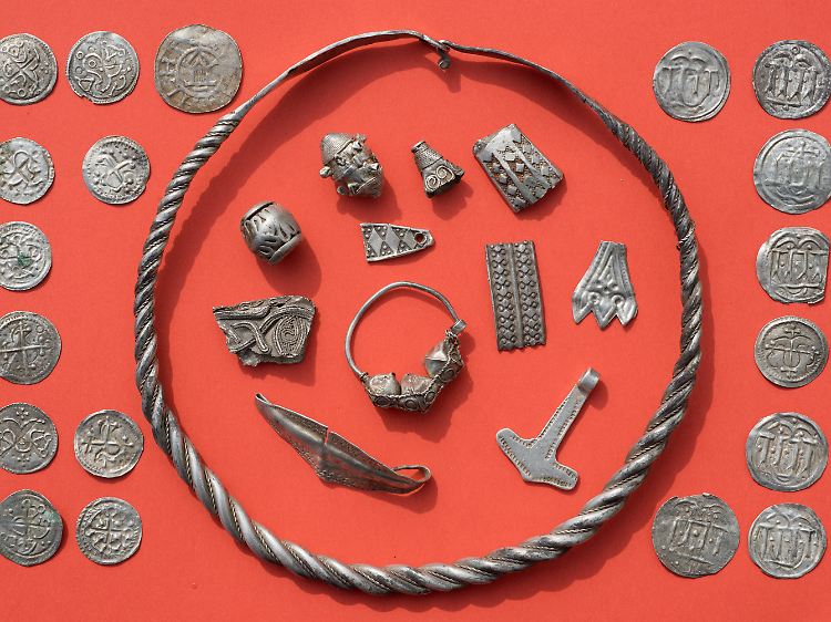 Teile des Silberschatzes mit gewendeltem, verschliessbarem Drahtring, Silberperlen mit Granulationsauflage, zerhacktem Silberschmuck, Thorshammeramulett und dänischen sowie ottonischen Münzen.