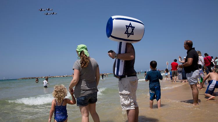 Am Strand verfolgt eine Gruppe Menschen die Flugshow zu Ehren des Unabhängigkeitstags.