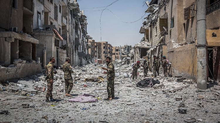 Soldaten der Syrischen Demokratischen Kräfte gehen an der Front in Al-Rakka während Gefechten mit der Terrormiliz Islamischer Staat (IS) durch einen zerstörten Straßenzug.