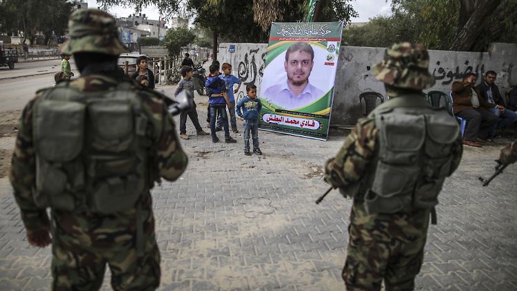Im palästinensischen Autonomiegebiet Dschabaliya stehen maskierte Kämpfer der Hamas vor dem Bild des ermordeten Ingenieurs Al-Batsch.