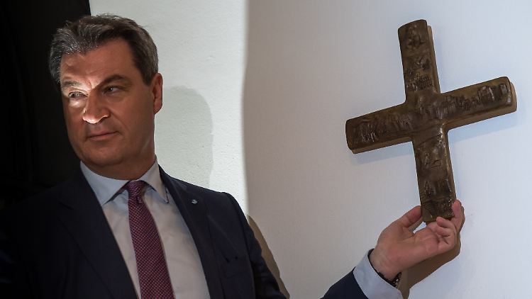 Landesvater Söder schreitet gleich zur Tat und hängt ein Kreuz auf.