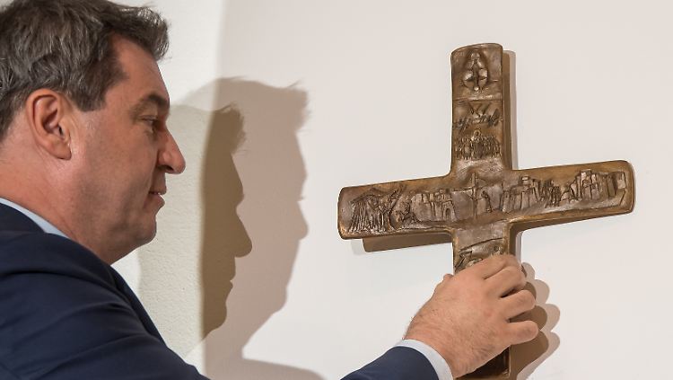Markus Söder hängt ein Kreuz auf.