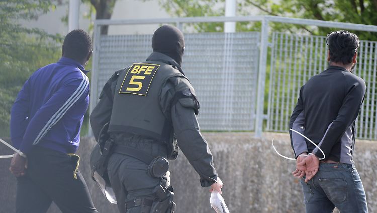 Ein Polizist führt zwei Menschen aus der Erstaufnahmeeinrichtung in Ellwangen ab.