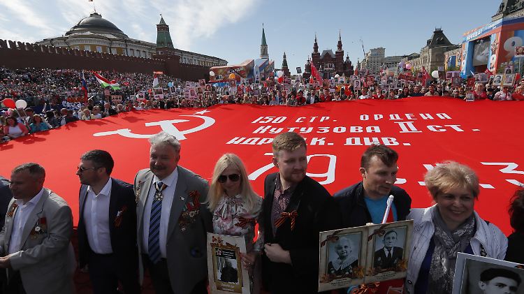 Teilnehmer der Aktion tragen eine Nachbildung des Siegesbanners und Bilder von Verwandten, die im Zweiten Weltkrieg gekämpft haben.