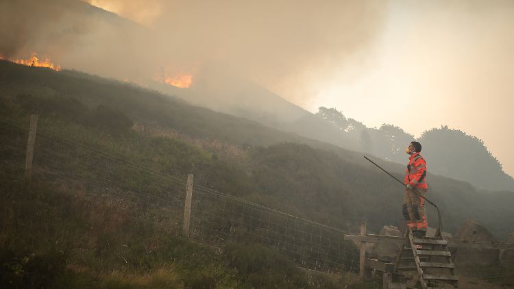 Ein Feuerwehrmann blickt auf den Großbrand, der sich im Saddleworth Moor und in Richtung der umliegenden Wohngegenden ausbreitet. 
