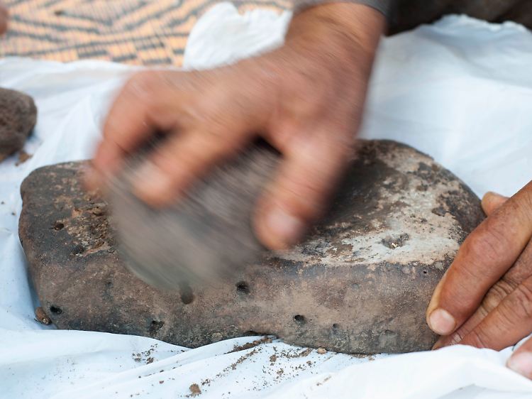Jordanien, Mafraq: Riedgras wird für die experimentelle Produktion von Mehl auf einem Stein gemahlen.