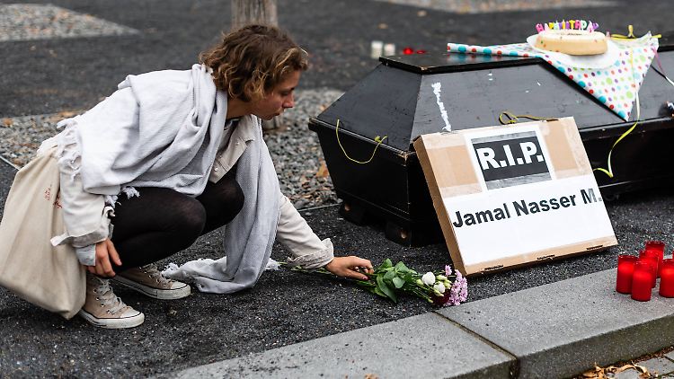 Eine Aktivistin legt Blumen neben einem Sarg vor dem Bundesinnenministerium nieder.