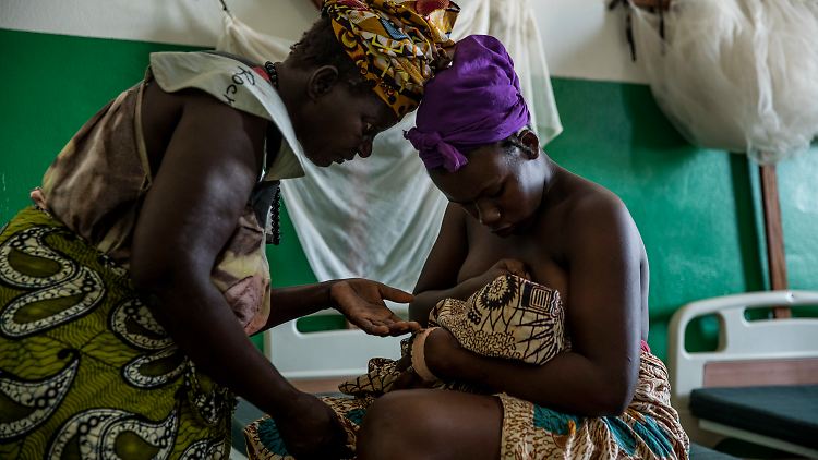 Eine junge Mutter stillt ihr Neugeborenes in einer Einrichtung der Unicef in Cacheu in Guinea-Bissau. Daneben steht die Großmutter des Babys.