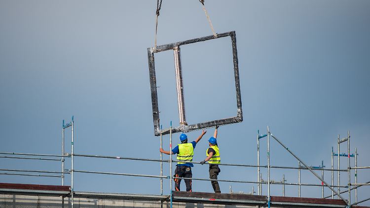 Zwei Bauarbeiter arbeiten auf einer Baustelle in der Hafencity in Hamburg. 
