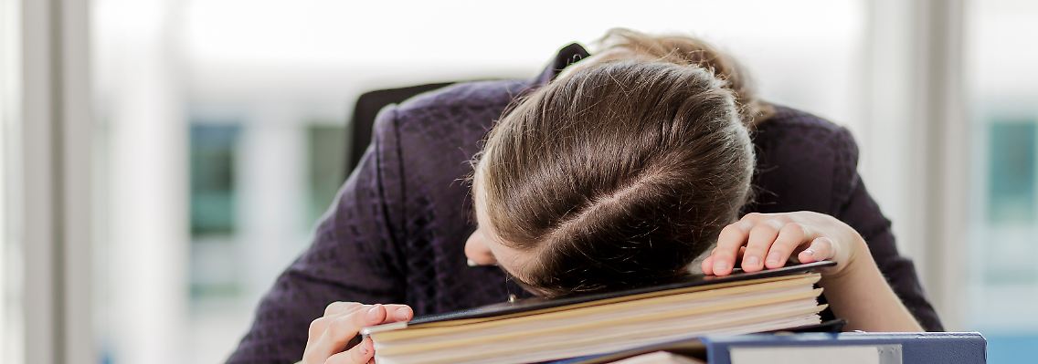 Power Nap gefällig? Eine Frau hält ein Mittagsschläfchen auf ihren Unterlagen.