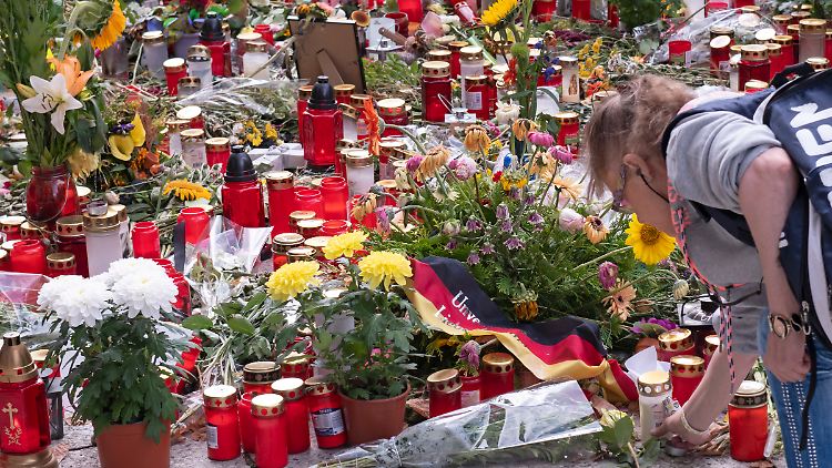 Eine Frau legt am Tatort Blumen nieder.