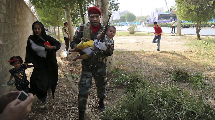 Ein Soldat versucht, eine Mutter mit ihren Kindern vor den Schüssen in Sicherheit zu bringen.