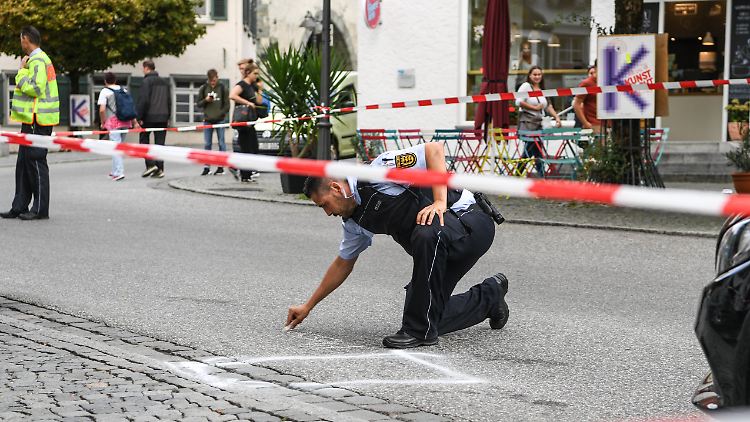 Ein Polizist markiert auf dem Ravensburger Marienplatz die Stelle, an der der Angreifer sein Messer fallen ließ.