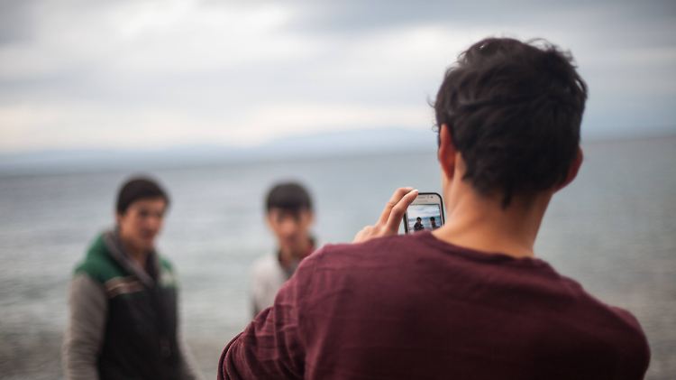 Ein Flüchtling fotografiert auf Lesbos seine Freunde. Kann er sich in Deutschland nicht ausweisen, dürfen Behörden sein Handy auslesen.