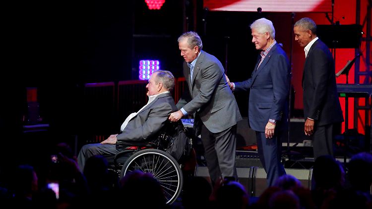 Bei einem Benefizkonzert nach einem Hurrikan in Texas helfen Bush junior, Clinton und Obama  dem nun verstorbenen Georg W. H. Bush (l.) im Rollstuhl von der Bühne. 