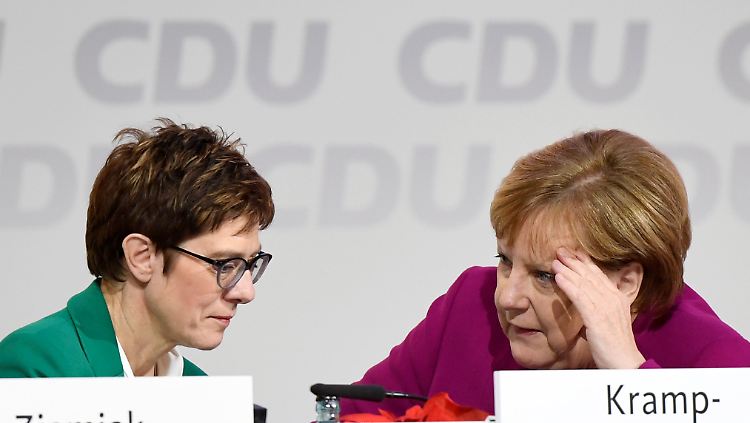 Annegret Kramp-Karrenbauer und Angela Merkel stecken die Köpfe zusammen.