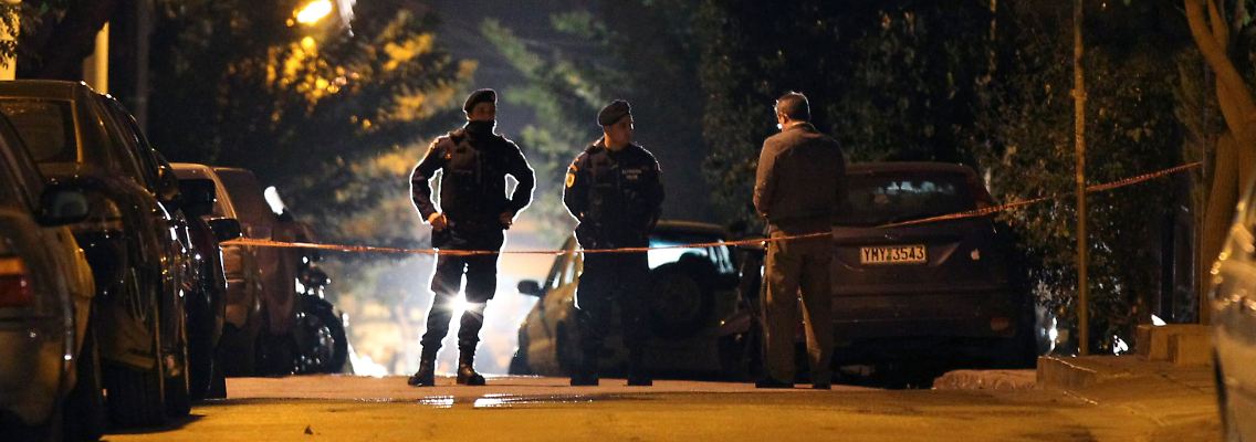 Polizisten sichern im Vorort von Athen die Gegen rund um die Razzia ab.