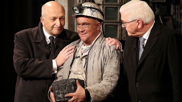 Peter Schrimpf, Vorstandsvorsitzender der Ruhrkohle AG und Bundespräsident Frank-Walter Steinmeier trösten den Reviersteiger mit dem letzten Stück Steinkohle.