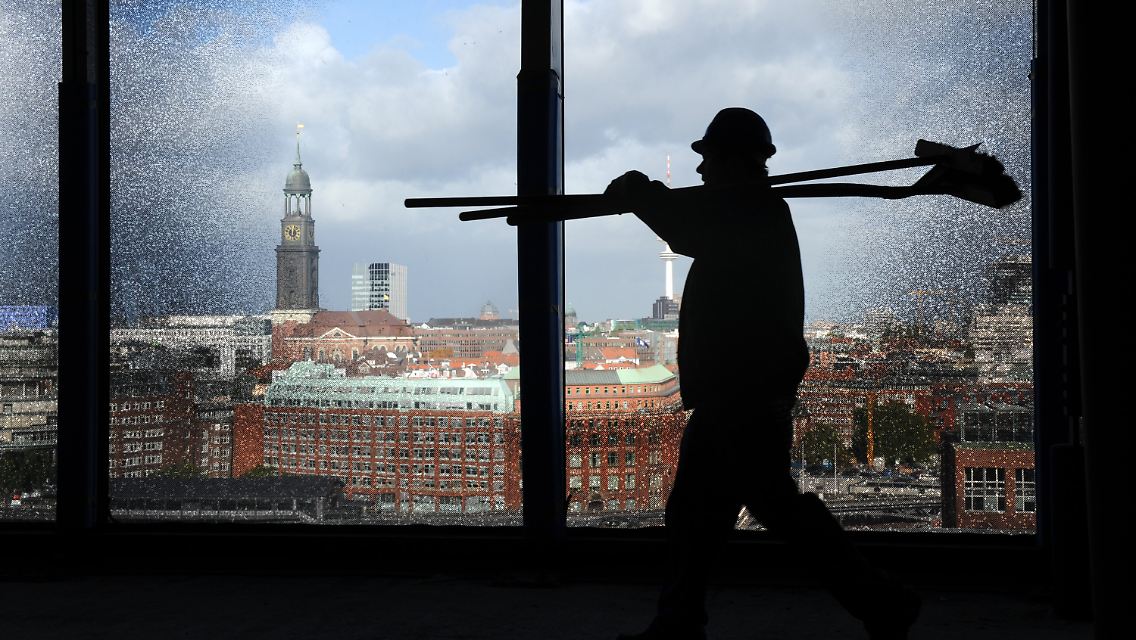 Ein Hochtief-Mitarbeiter geht in Hamburg auf der Baustelle der Elbphilharmonie an einem Spezialfenster vorbei.