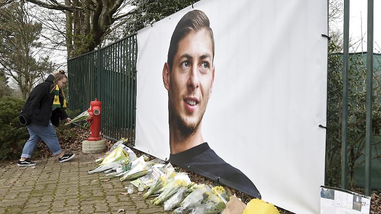 Am Trainingsgelände des FC Nantes legt ein Fan Blumen vor ein Transparent Salas.